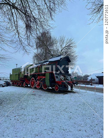 Poland, Przeworsk. December 2023. Old steam locomotive in the yard of a country house in winter standing as museum exposition 120771611