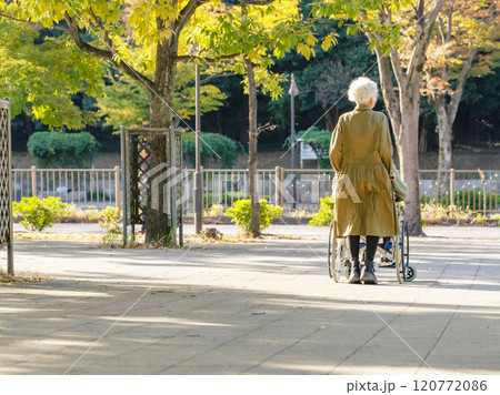 車椅子に乗った男性と介助する女性のシニアカップル 車椅子に乗った男性と介助する女性のシニアカップル 120772086