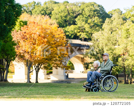 公園で空を見上げる車椅子に乗ったシニアカップル 公園で空を見上げる車椅子に乗ったシニアカップル 120772105