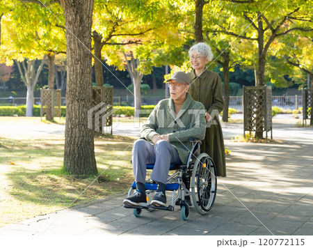車椅子に乗った男性と介助する女性のシニアカップル 車椅子に乗った男性と介助する女性のシニアカップル 120772115