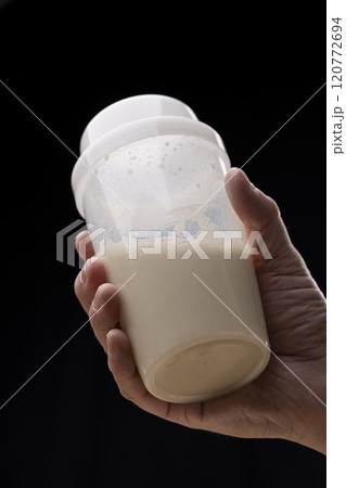 黒背景でプロテインシェイカーを持つ男性の手 120772694