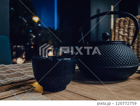 Black teapot and kettle on a wooden table with cups for tea in a Asian tea and sushi house 120772759