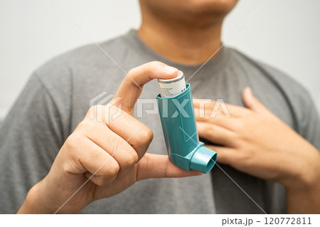 Asthma and chronic obstructive pulmonary disease COPD, Asian young man using metered dose inhaler MDI. 120772811