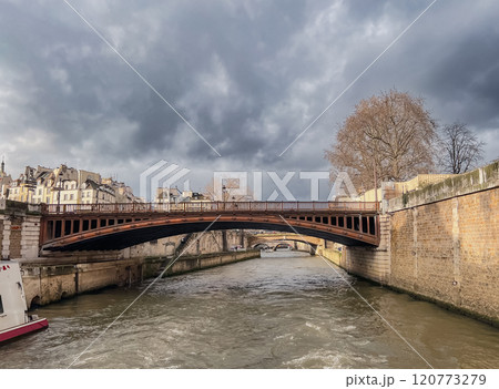 River Seine in Paris, France. Beautiful cityscape with cloudy sky with the view on the houses and bridge from a boat. 120773279