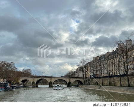 River Seine in Paris, France. Beautiful cityscape with cloudy sky with the view on the houses and bridge from a boat. 120773924