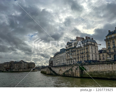 River Seine in Paris, France. Beautiful cityscape with cloudy sky with the view on the houses and bridge from a boat. 120773925