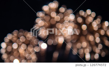 Blurry image of fireworks with a lot of light and dark spots 120774372