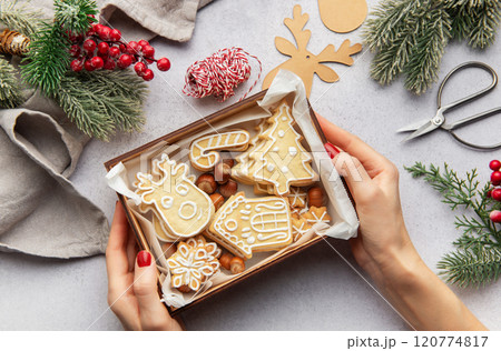 Woman holding christmas cookies in wooden box with festive decorations 120774817