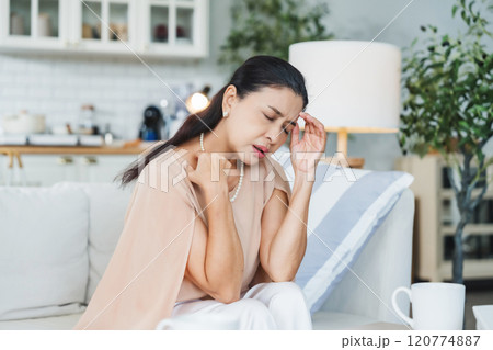 Upset Asian senior woman sitting on sofa, lost in thoughts, feeling lonely Upset Asian senior woman sitting on sofa, lost in thoughts, feeling lonely 120774887