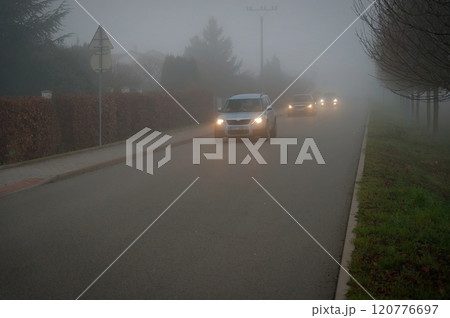Car on the road in the fog. Autumn landscape - dangerous road traffic in winter season. 120776697