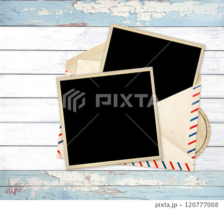 Top view of blank vintage aged opened letter paper envelope with striped edges and two photo and card inside. Retro photos in old envelope with blank card on old wooden boards 120777008