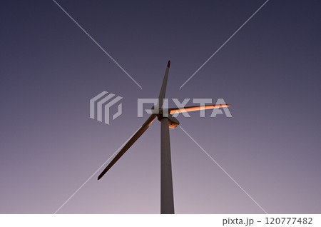 夕日に照らされる風力発電機 120777482