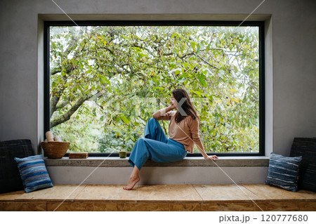 Beautiful woman sitting in front of large window, clean space. Beautiful woman sitting in front of large window, clean space. 120777680