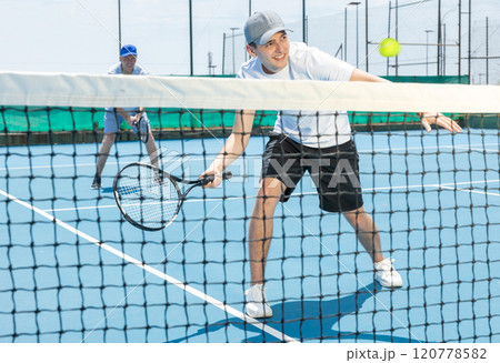 Man in shorts and t-shirt playing tennis on court. Racket sport training outdoors 120778582