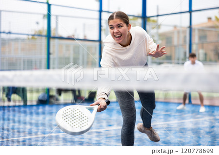 Sporty young girl playing padel on open court Sporty young girl playing padel on open court 120778699