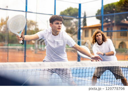 Male player ready to hits the ball while playing padel on hard court Male player ready to hits the ball while playing padel on hard court 120778706