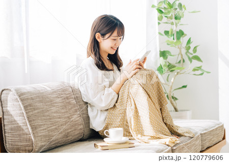 ソファに座ってスマホを見る女性 120779606