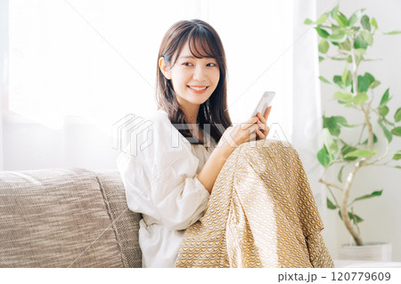 ソファに座ってスマホを見る女性 120779609