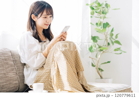 ソファに座ってスマホを見る女性 120779611