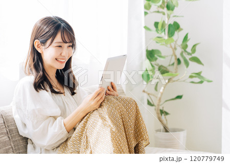 ソファに座ってタブレットを見る女性 120779749