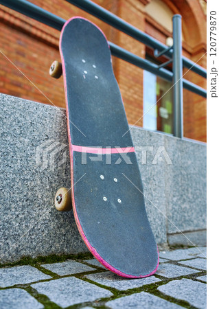 Used scratched pink skateboard against stone wall at city street. Urban sport and youth subculture concept 120779870