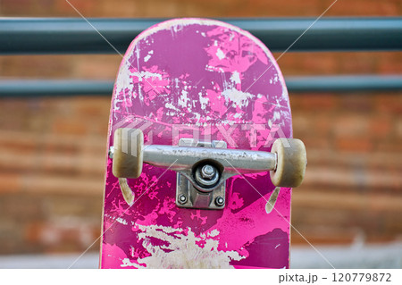 Used scratched pink skateboard against stone wall at city street. Urban sport and youth subculture concept 120779872