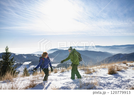Active seniors having snowball fight. Romantic winter hike for an elderly couple in snowy mountains. 120779913