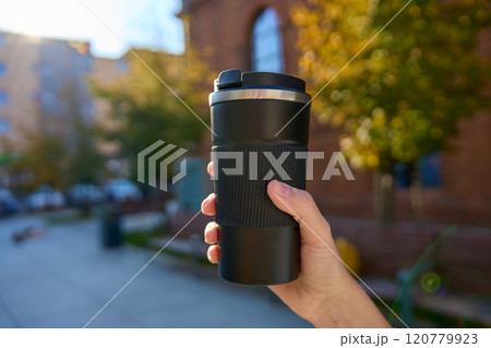 Woman holding reusable coffee cup on blurred autumn background. Concept of sustainable and eco-friendly living Woman holding reusable coffee cup on blurred autumn background. Concept of sustainable and eco-friendly living 120779923