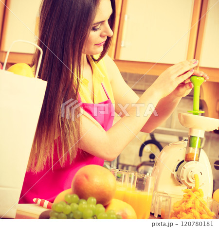 Woman making orange juice in juicer machine Woman making orange juice in juicer machine 120780181