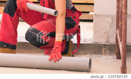 Woman carrying pipes on construction site 120780195