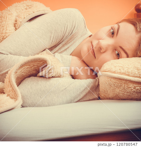 Woman relaxing napping in bed under wool blanket. 120780547