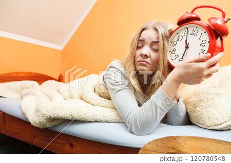 Unhappy woman waking up with alarm clock. 120780548