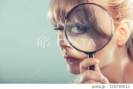 Woman hand holding magnifying glass on eye 120780612