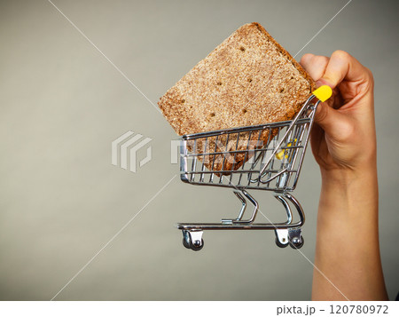 Woman hand holding shopping cart with bread Woman hand holding shopping cart with bread 120780972