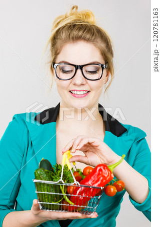 Woman holds shopping basket with vegetables 120781163