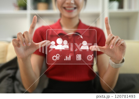 Smiling young woman interacting with virtual icons representing business analytics and management 120781493