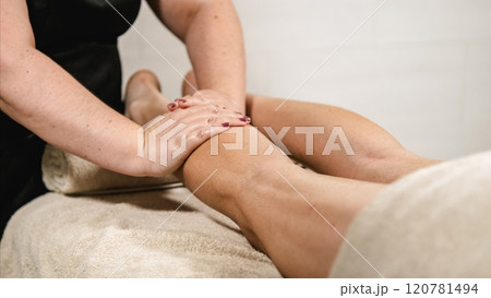 Masseuse giving leg massage to client in spa Masseuse giving leg massage to client in spa 120781494