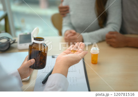 Doctor holding a bottle of pills and explaining a treatment plan to patient Doctor holding a bottle of pills and explaining a treatment plan to patient 120781516
