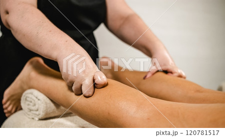 Masseuse giving leg massage to client in spa Masseuse giving leg massage to client in spa 120781517