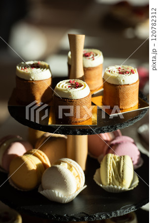 A table with a variety of desserts and pastries. The desserts are arranged in glass bowls and trays 120782312