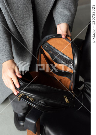 woman holds a black leather backpack. open, empty bag 120782325