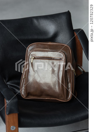 Brown leather backpack on the stylish chair Brown leather backpack on the stylish chair 120782329