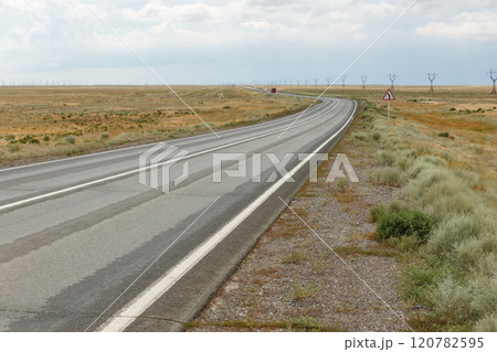 Expansive highway stretching through the serene landscape of Kazakhstan's steppe region 120782595