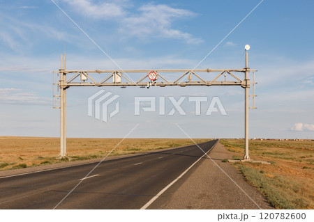 Road sign and warning signal over an empty highway in Kazakhstan's vast steppe region 120782600