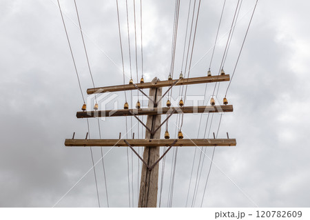 Overhead communication line connected to wooden utility pole against a cloudy sky 120782609