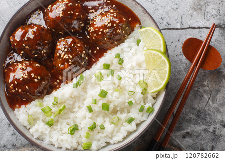 Asian meatballs coated in the sweet and spicy sauce made with sriracha, soy sauce, ginger, honey and garlic served with rice closeup on the bowl. Horizontal top view 120782662