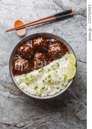 Sticky honey sriracha meatballs with rice closeup on the bowl. Vertical top view 120782663