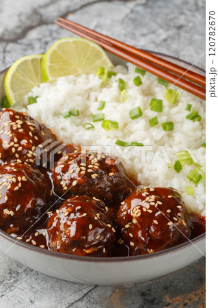 Sweet and spicy meatballs in honey sriracha sauce served with rice close-up in a bowl. Vertical 120782670