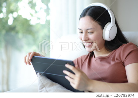 Happy asian woman with headphone watching video on tablet 120782974