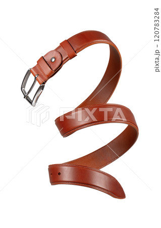 Brown leather belt with metal buckle coiled in a close-up on a white background. 120783284